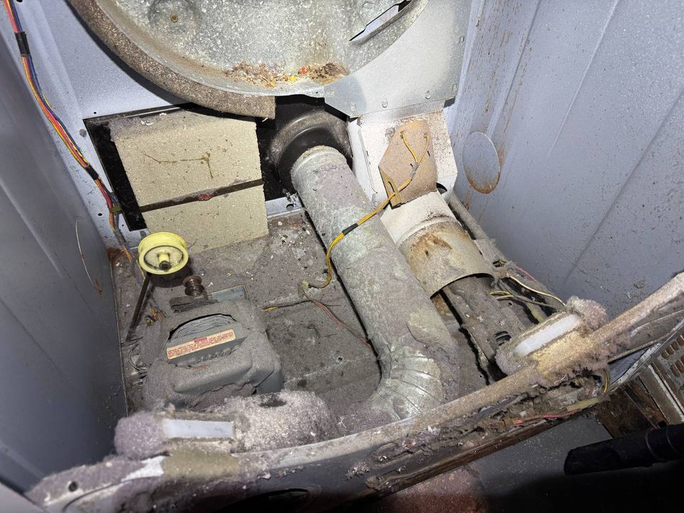 Inside a GE gas dryer cabinet packed with lint around the blower housing and duct