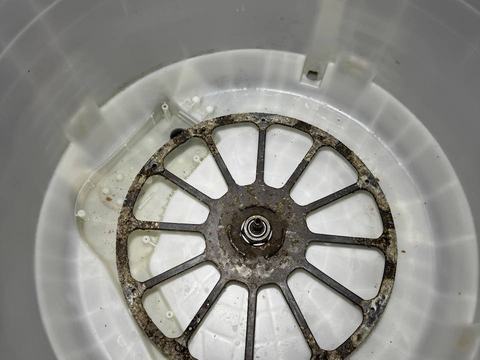 Washer tub base covered in dark buildup before cleaning